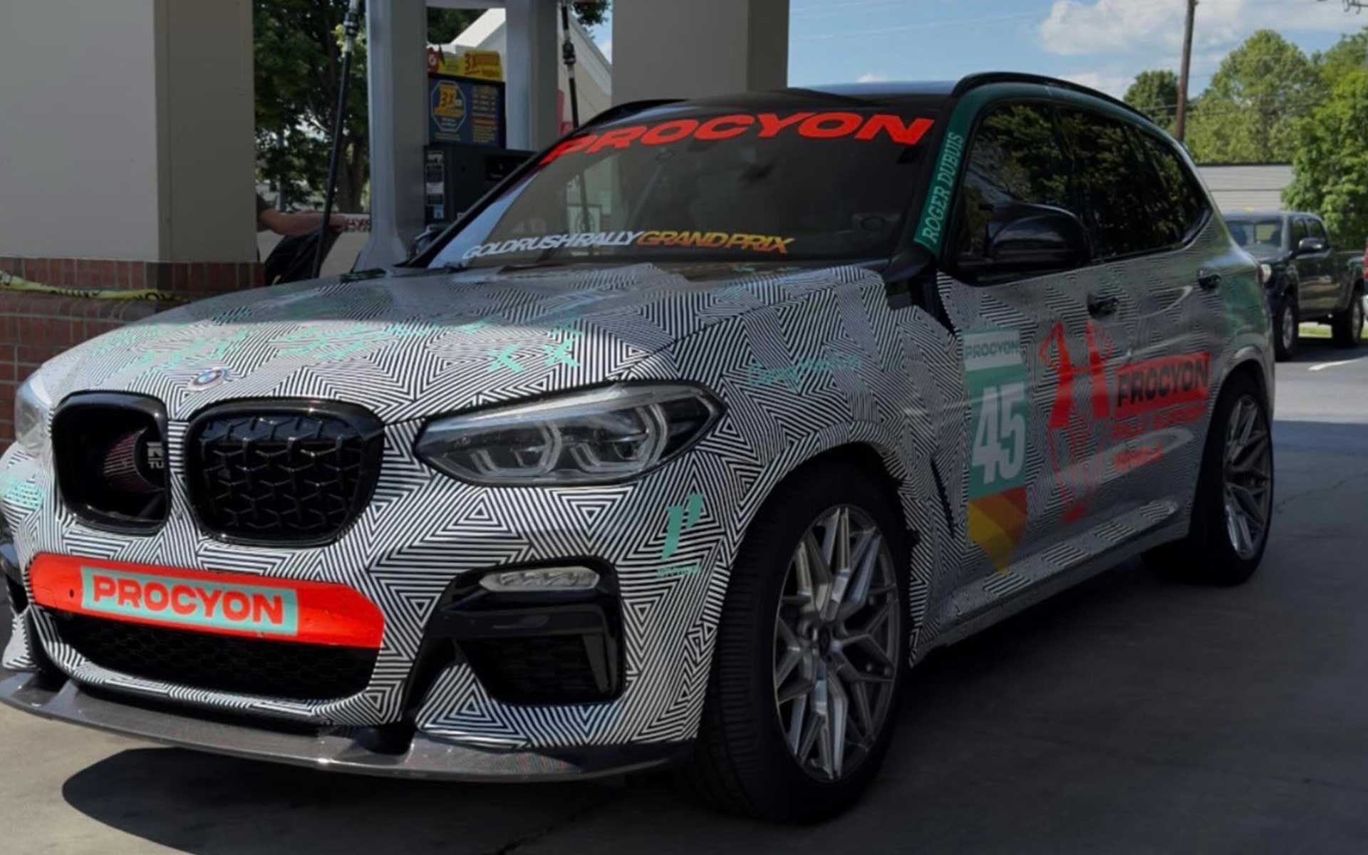 A bmw x4 is parked in front of a gas station.