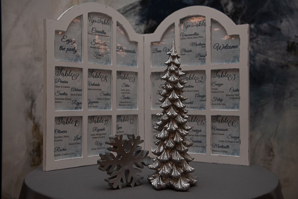 A white framed seating chart, decorated with a silver tree and snowflake.