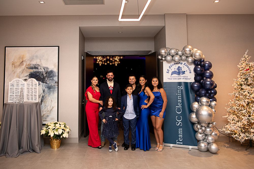 Family posing at a formal event, balloons, Christmas tree, entrance with logo
