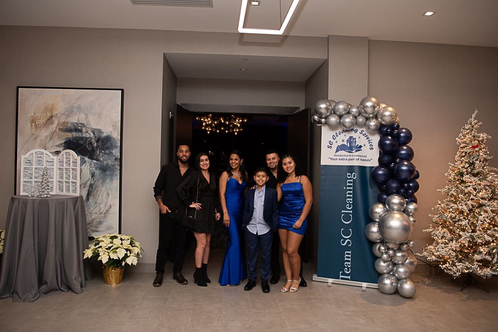 Group poses at an event with balloons and a Christmas tree. Formal attire.