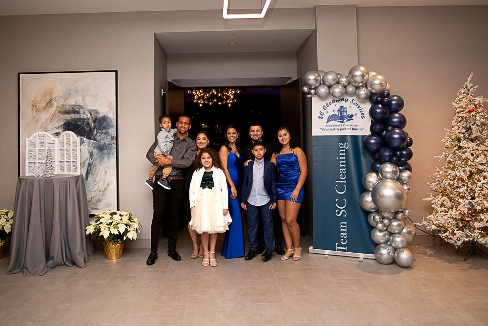 Family poses at an event with balloons and a Christmas tree.