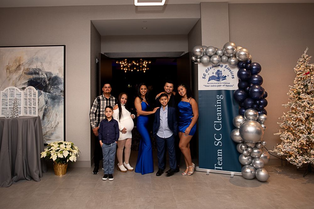 Family poses for photo at event with balloon arch and Christmas tree.