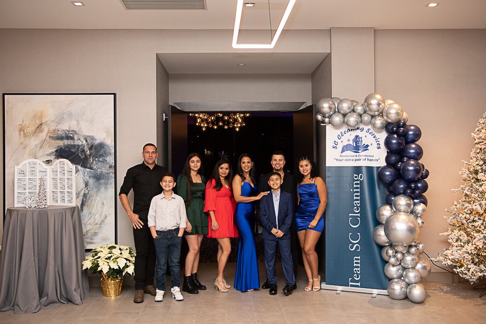 Family poses at an event with a balloon arch. The group is in formal attire.