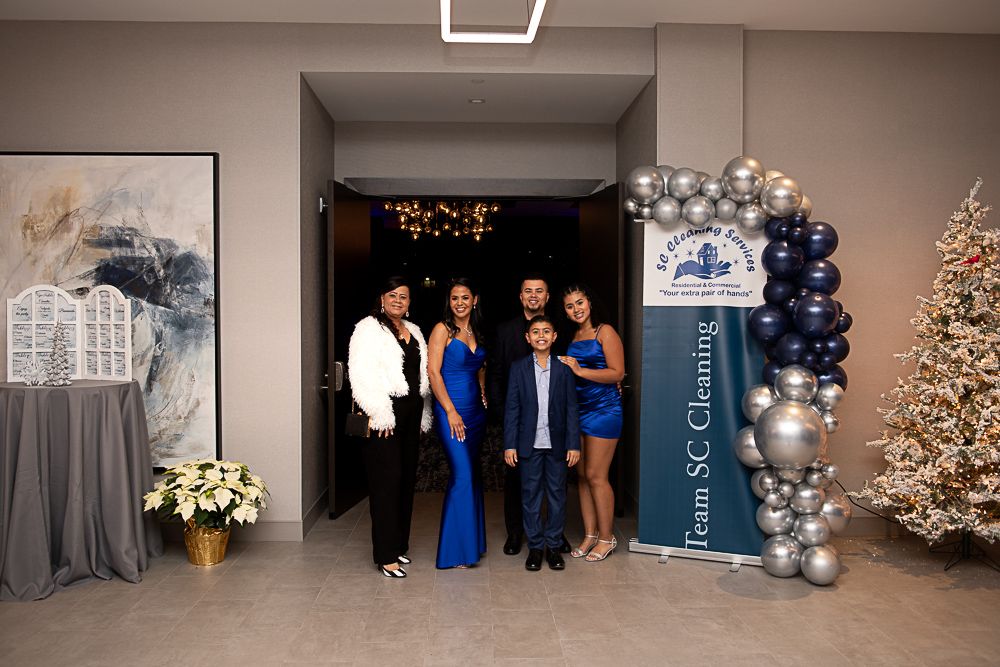 Family poses at an event entrance with balloon arch and Christmas tree.