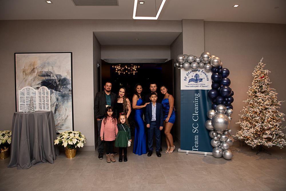 Family poses at an event entrance, featuring an arch of balloons and a Christmas tree.