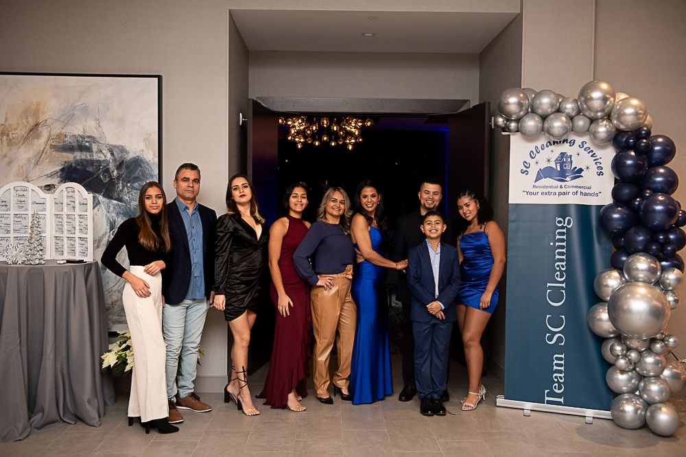 Group of diverse people posing at an event with balloons and a banner that says