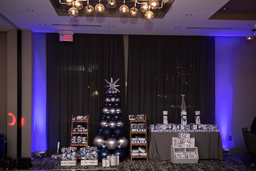 A decorated holiday display with a balloon Christmas tree, gifts, and table with items.
