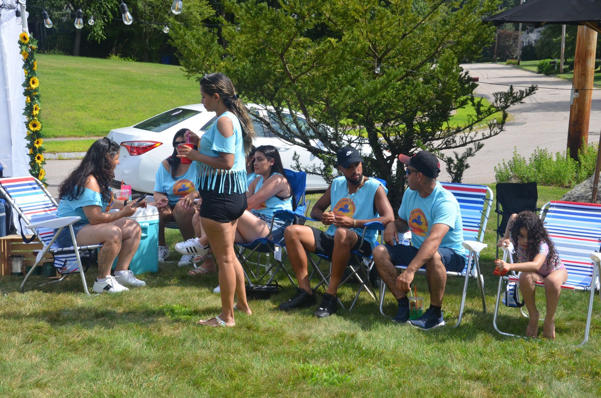Group of people in matching blue shirts sitting and standing outside on a lawn.