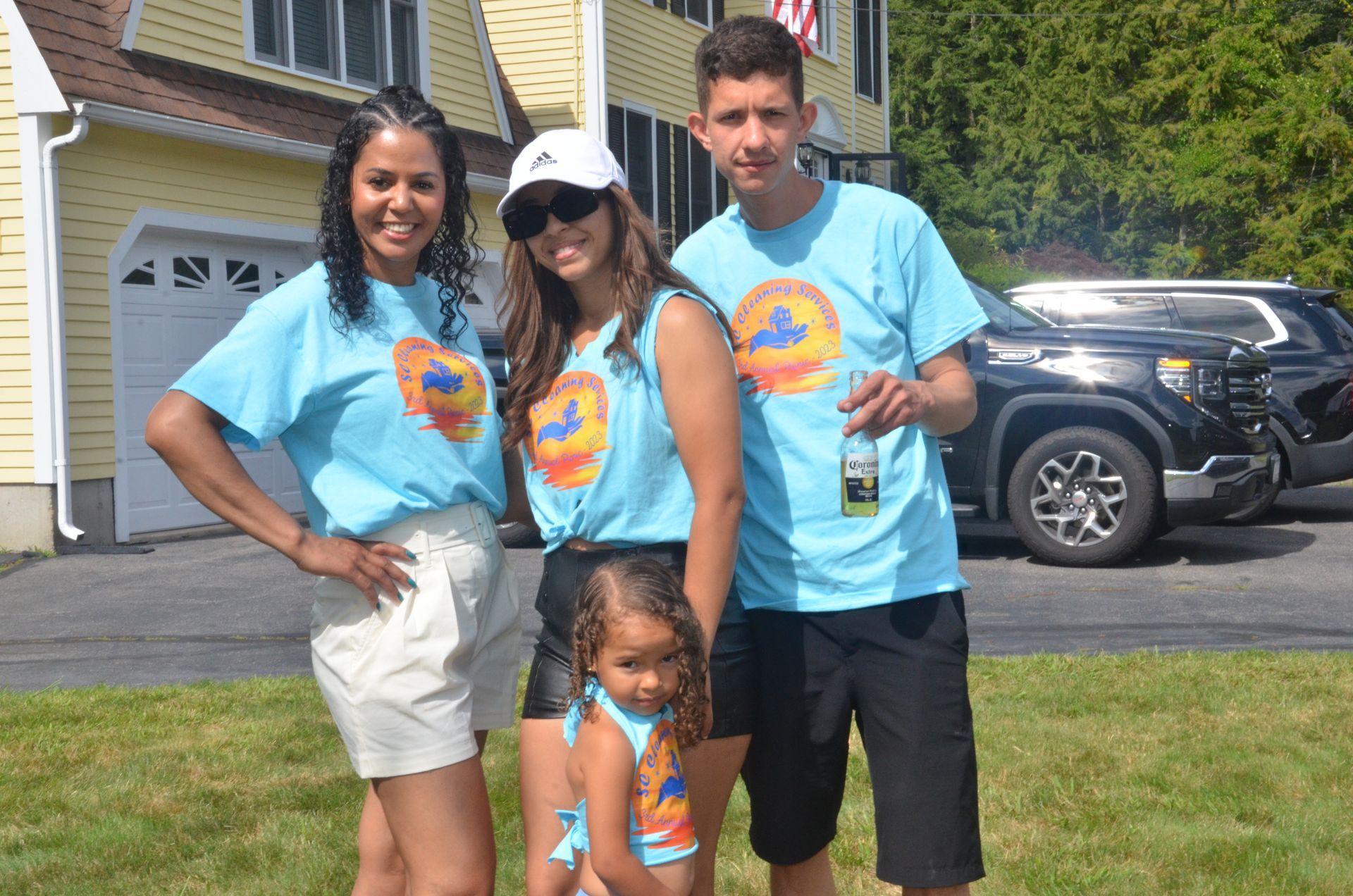 Family in blue shirts poses outside a yellow house.