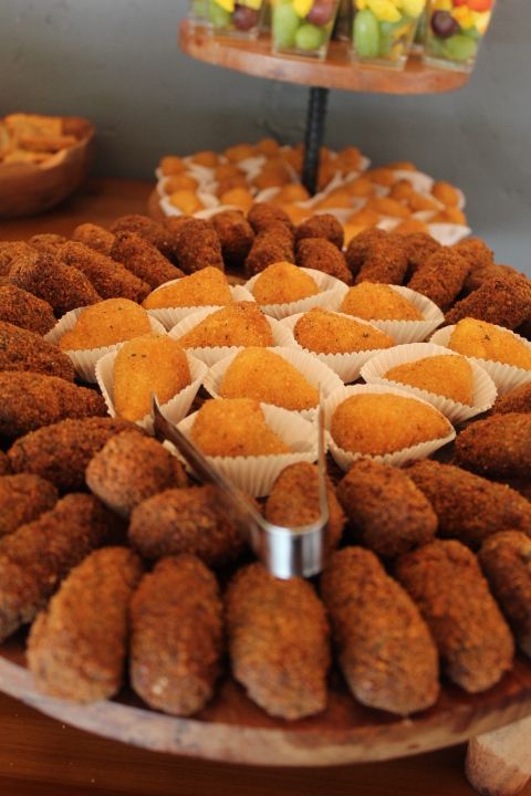 Tray of assorted fried savory snacks at a gathering, including croquettes and pastries.