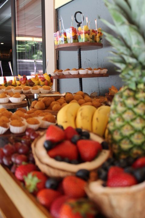 Fruit and pastries buffet, including strawberries, grapes, mangoes, pineapple, and baked goods, attractively arranged.