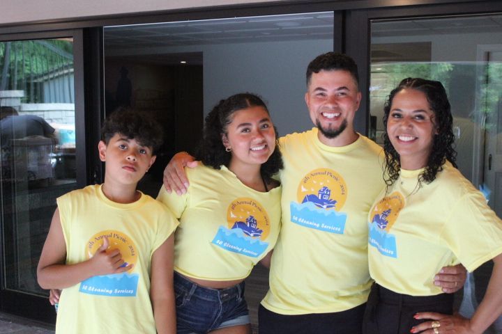 Family of four wearing yellow shirts, smiling, posing by a doorway.
