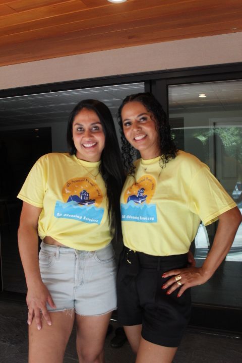 Two women in yellow shirts and shorts pose outdoors.