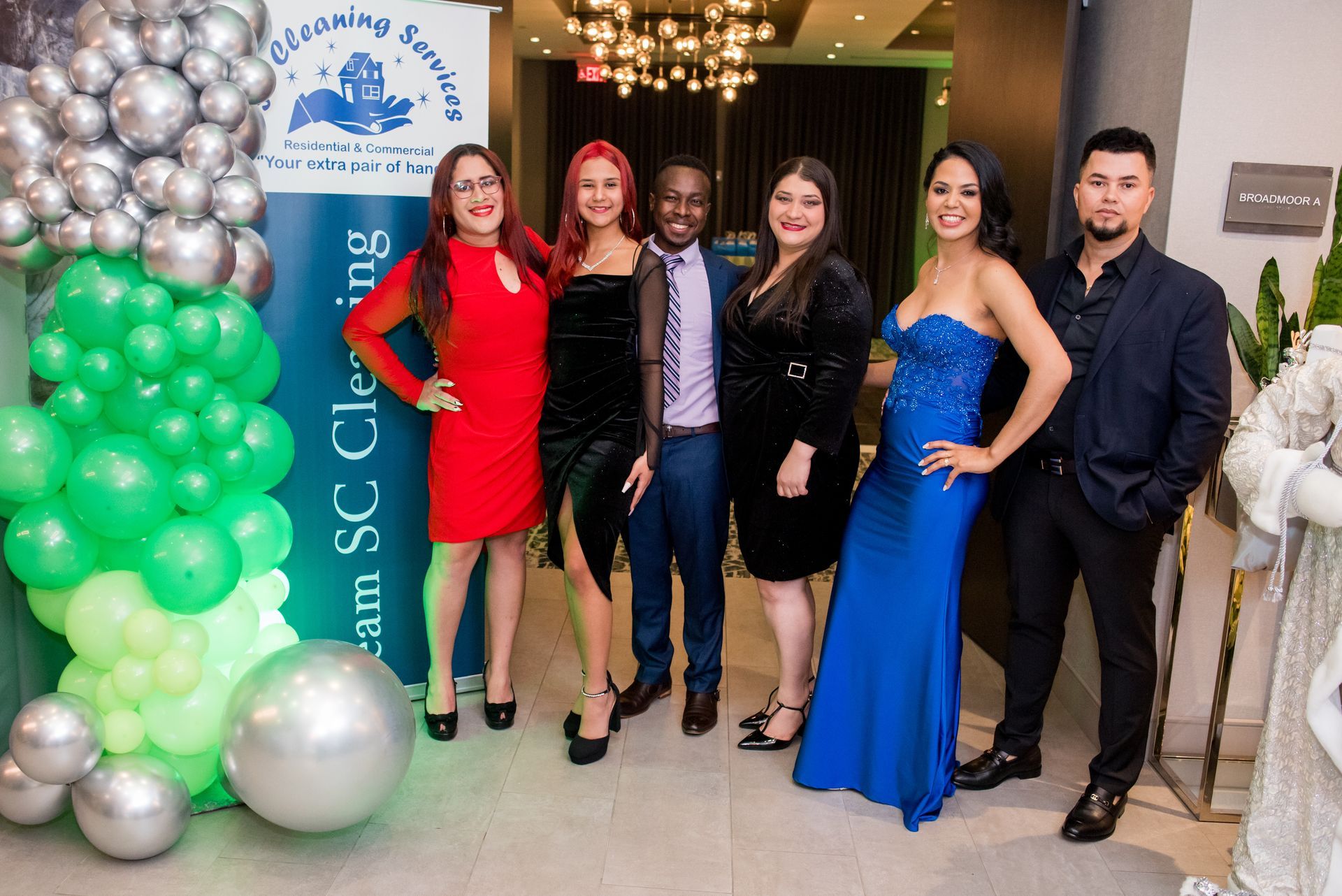 Group of six people in formal attire posing for photo with balloons.