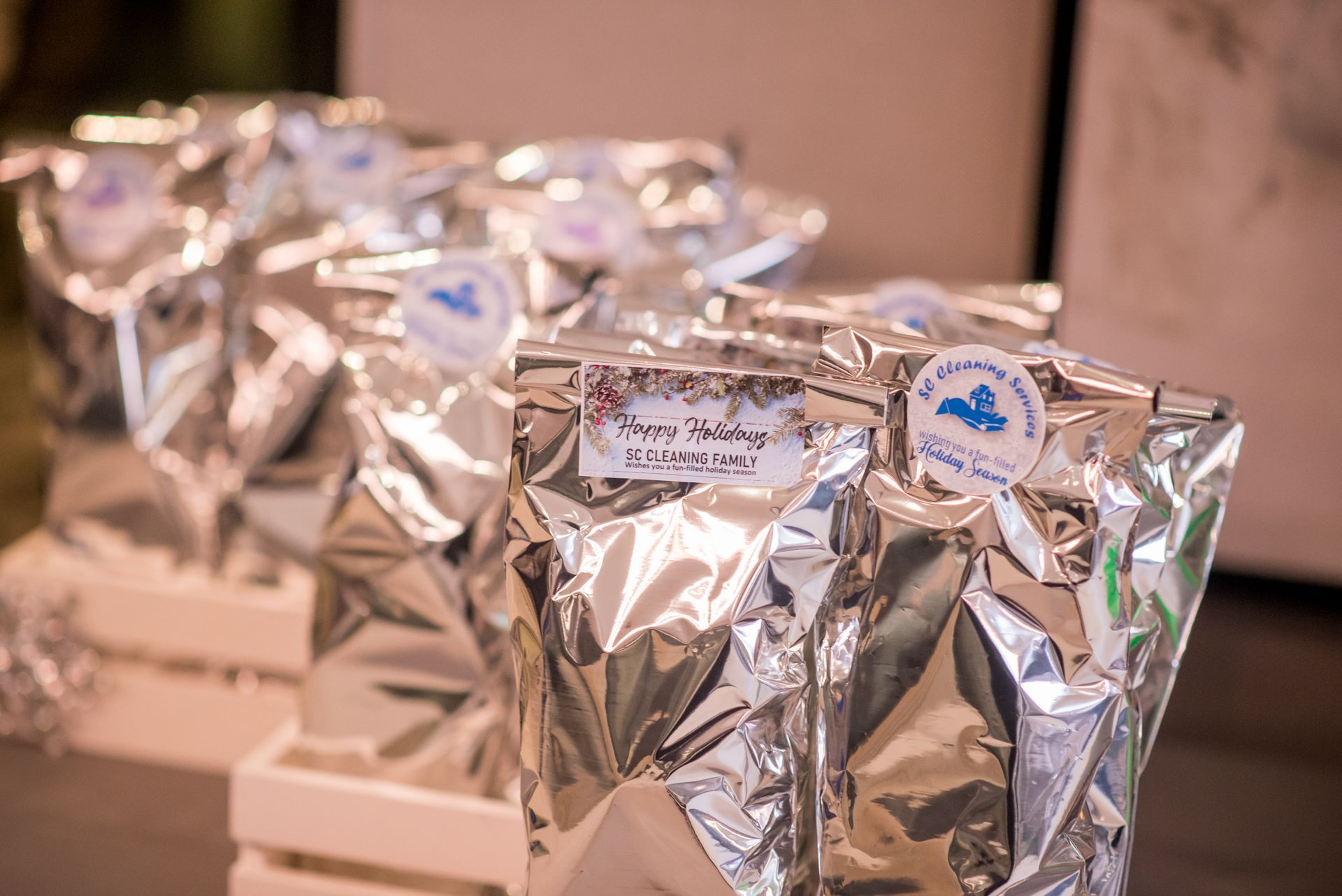Bags of food in silver foil packaging, labeled with round stickers and handwritten names, on wooden crates.