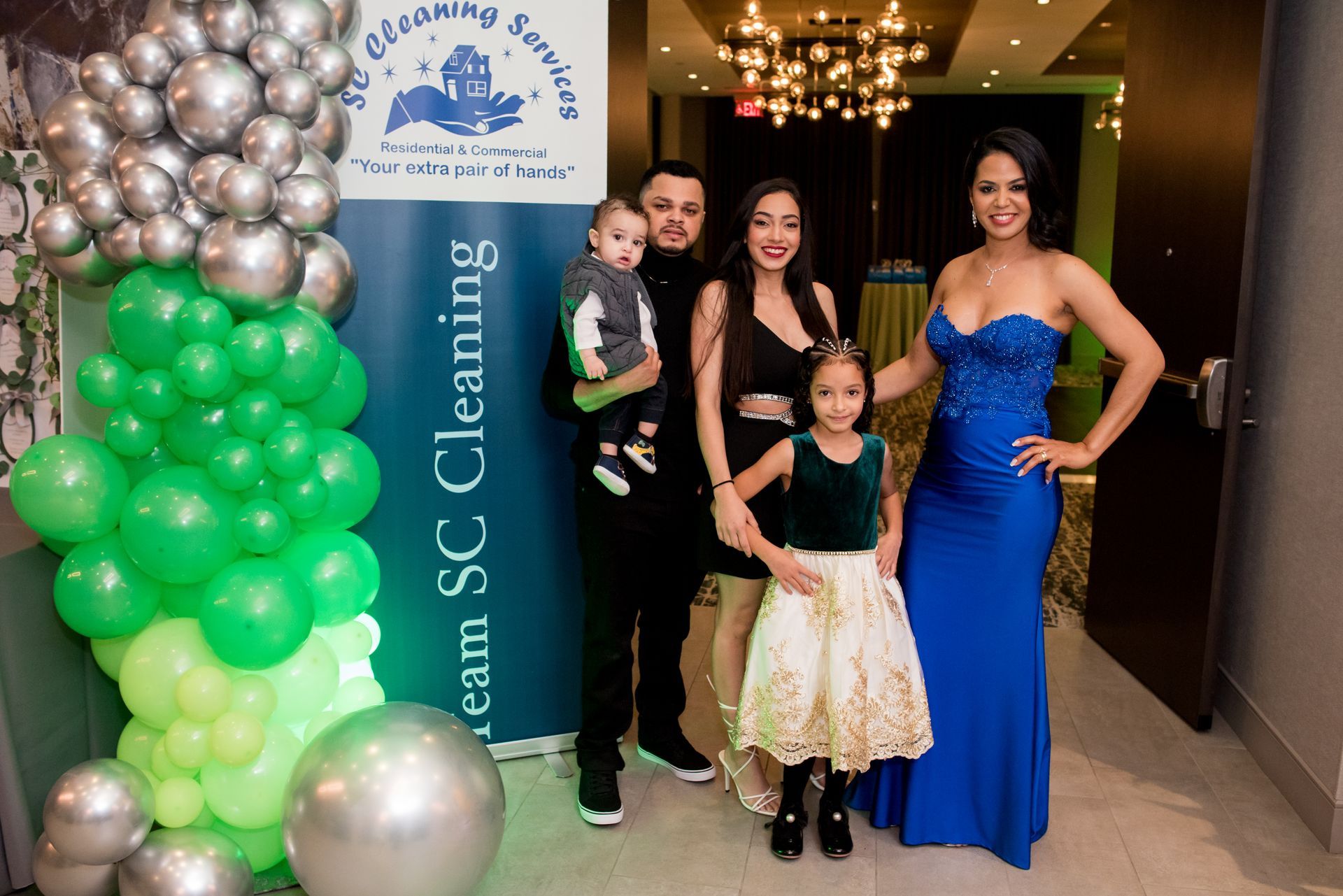 Family poses with SC Cleaning sign, next to balloon archway.
