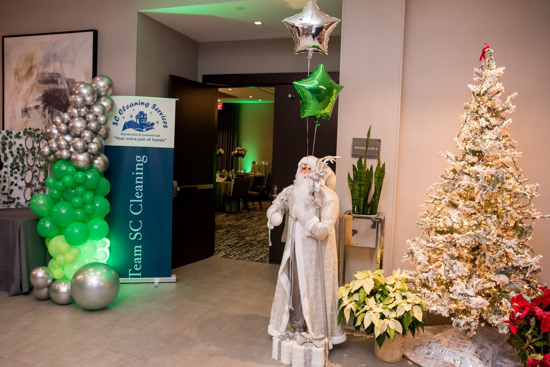 Decorated entrance with balloons, Christmas tree, Santa statue, and banner for Team SC Cleaning.