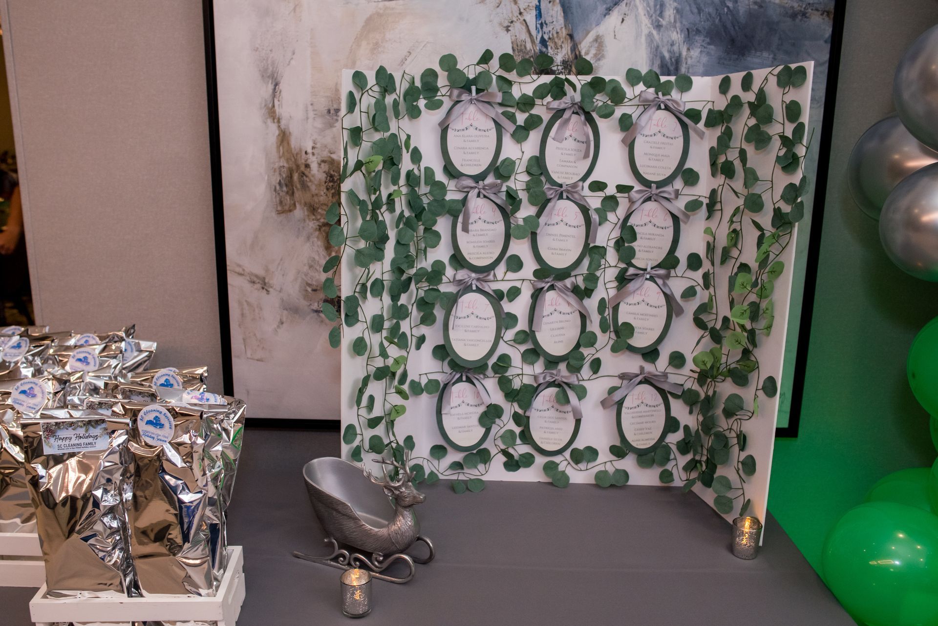 Seating chart with greenery and silver bows; silver favors, a small tub, and balloons.