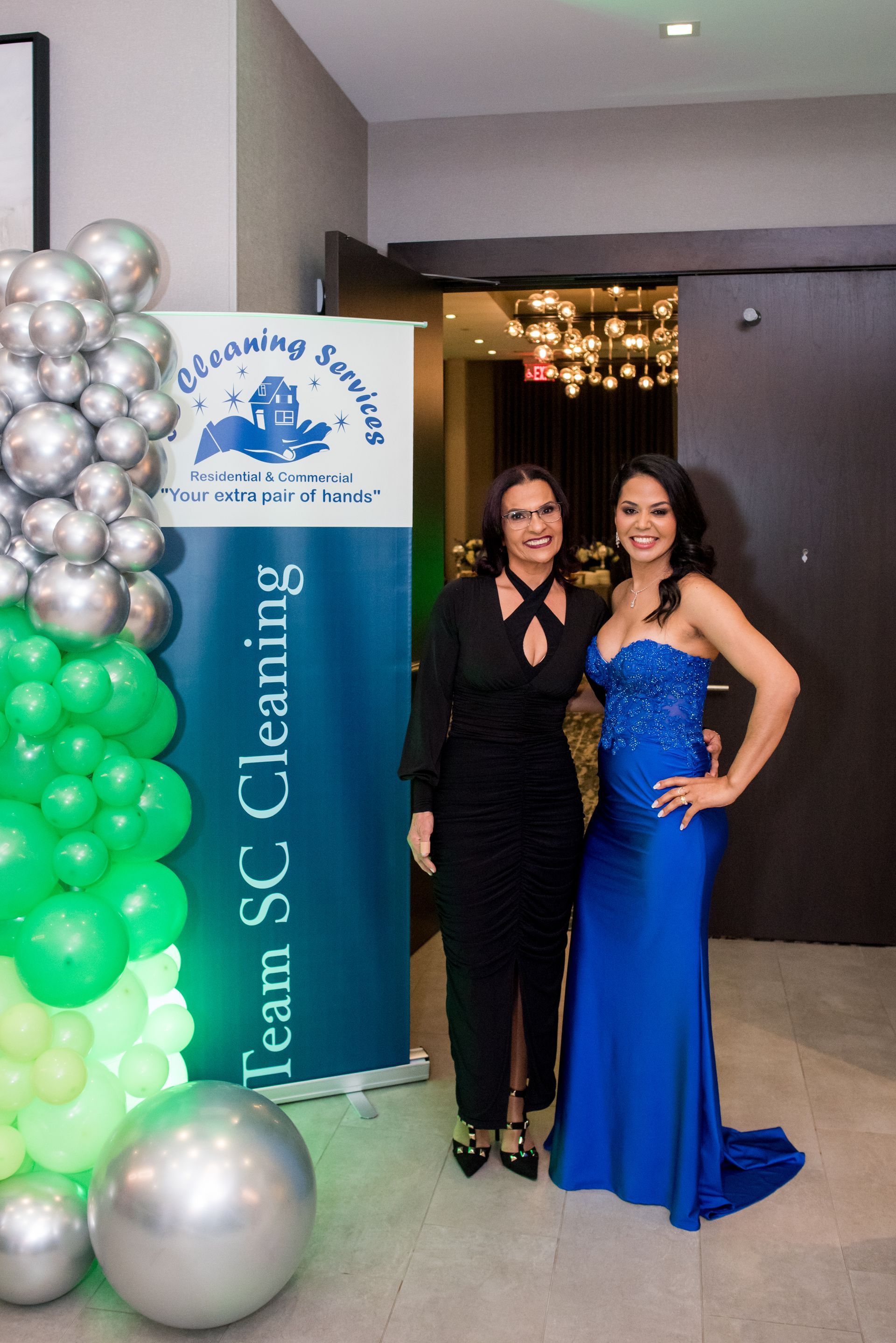 Two women pose by a banner for