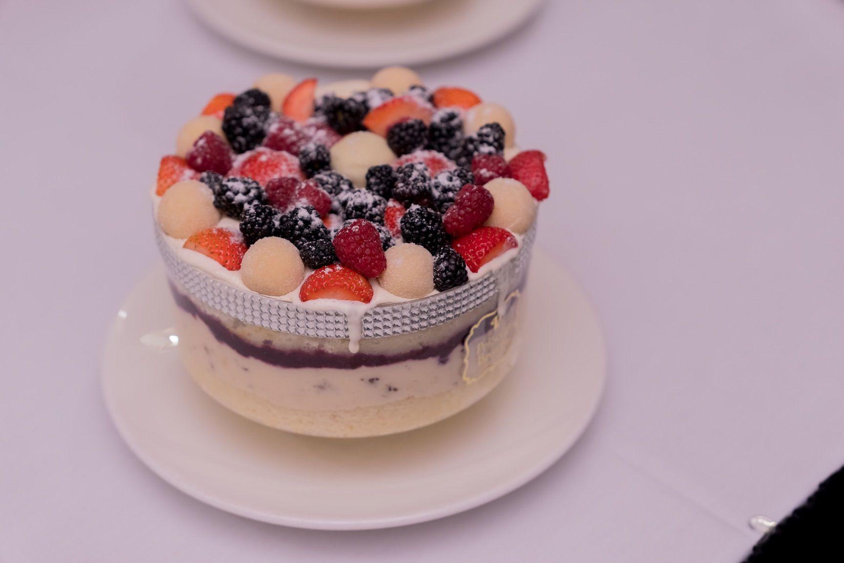 Cake decorated with berries and white chocolate, on a white plate.