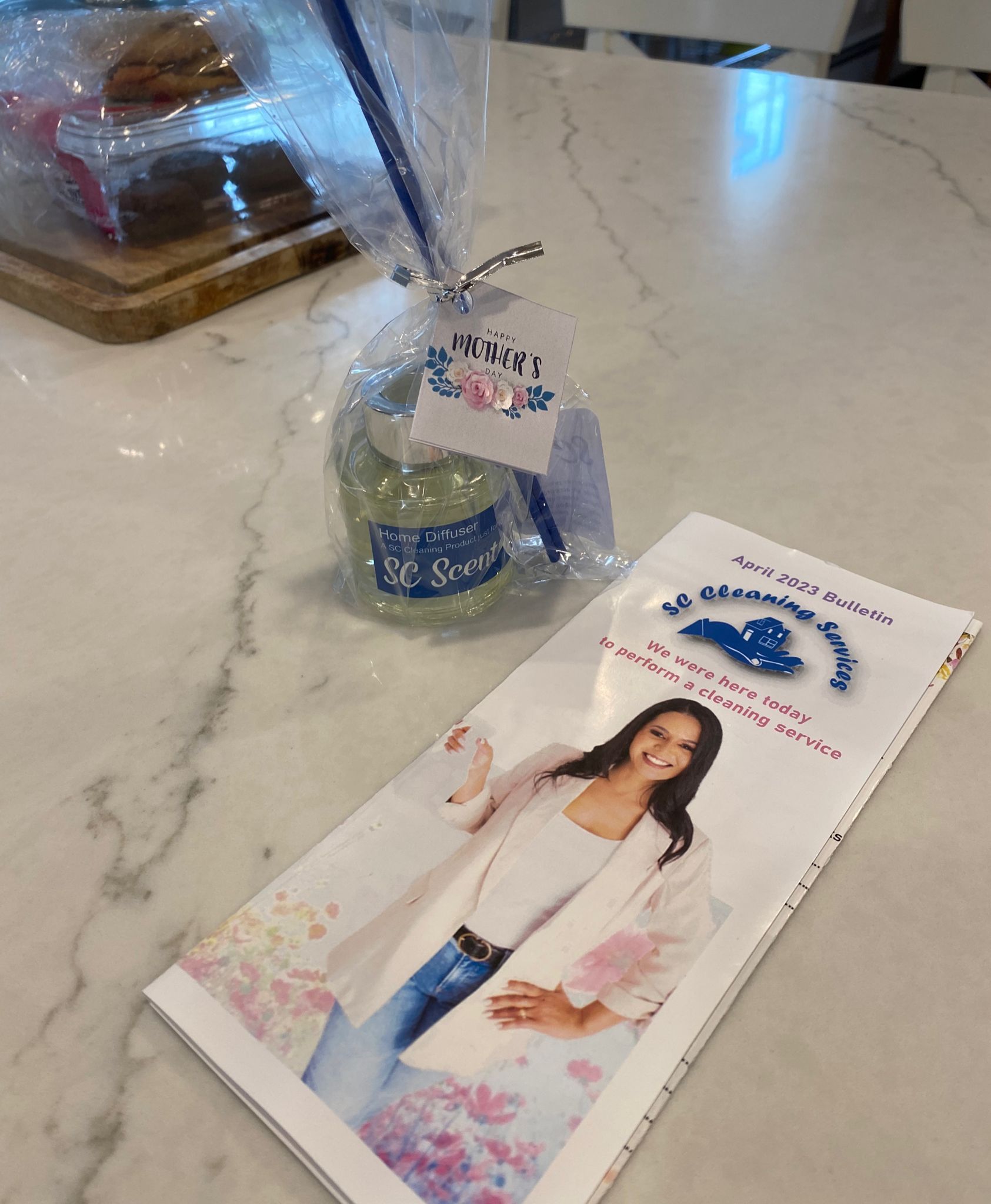 A gift bag and brochure on a table, featuring a woman smiling and a floral design.