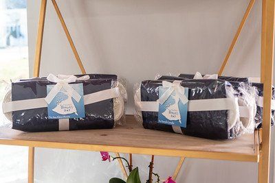 Shelf with wrapped gifts in dark blue paper, white ribbons, and tags, inside a store.