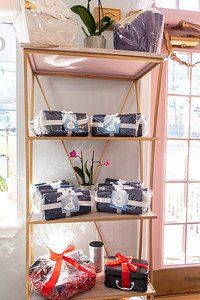 Shelving unit with gifts wrapped in cellophane and tied with ribbons, featuring orchids and a canister.