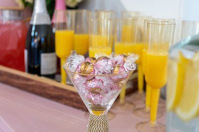 A festive brunch spread: orange juice, champagne, pink lemonade, and chocolates in a martini glass.