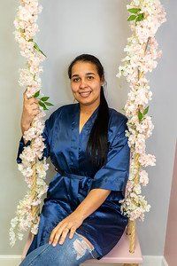 Woman in blue robe on a floral swing, smiling.