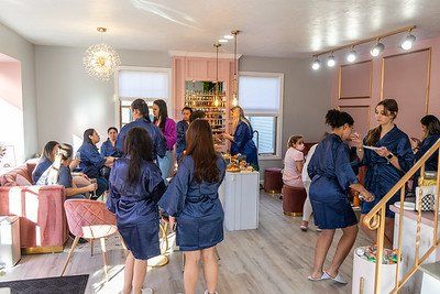People in blue robes at a pink-themed spa, celebrating with food and drinks.