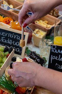 Person uses honey dipper over a cheese and fruit platter.