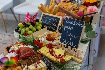 Charcuterie board with fruit, cheese, breadsticks, and handwritten chalkboard messages.