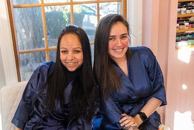 Two smiling women in blue robes by a window.