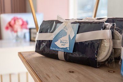 Wrapped gift set with blue packaging, white ribbon, and a product tag on a wooden shelf.