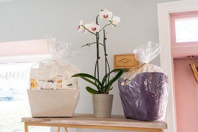 A shelf with an orchid, gift baskets wrapped in cellophane, against a light blue wall.