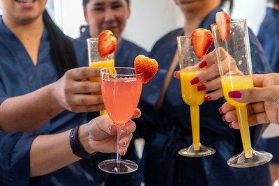 Group of women in blue robes toasting with cocktails, some with strawberries.