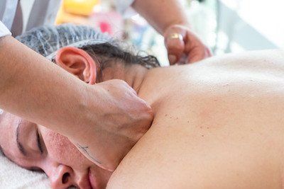 Person receiving a neck massage from a masseuse at a spa.
