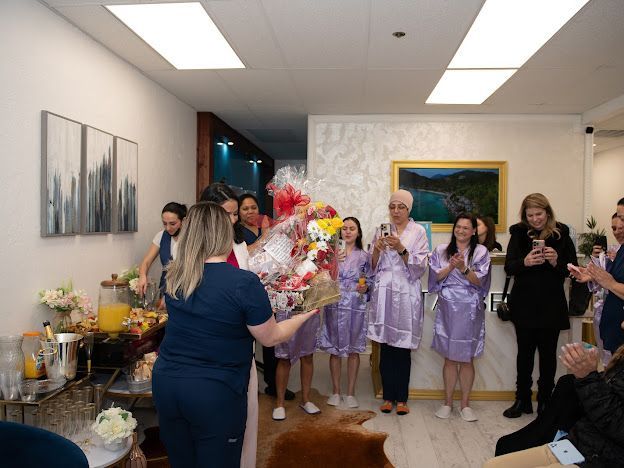 A group of people are standing in a room with a woman holding a bouquet of flowers.