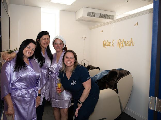 A group of women are posing for a picture in a room that says relax and refresh.