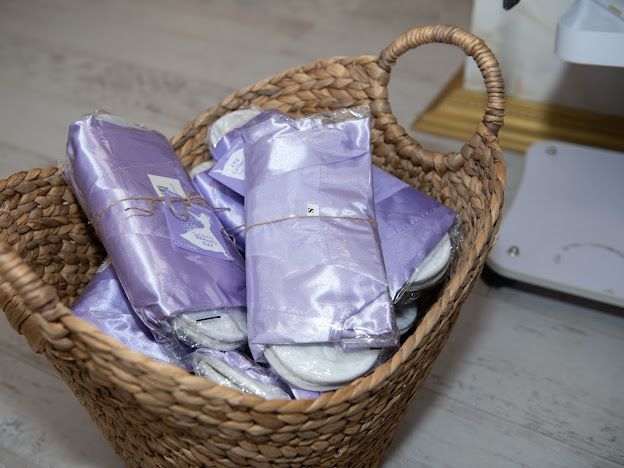 A basket filled with purple slippers is sitting on a table.