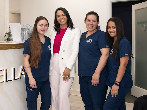 A group of women are posing for a picture in front of a sign that says ella.