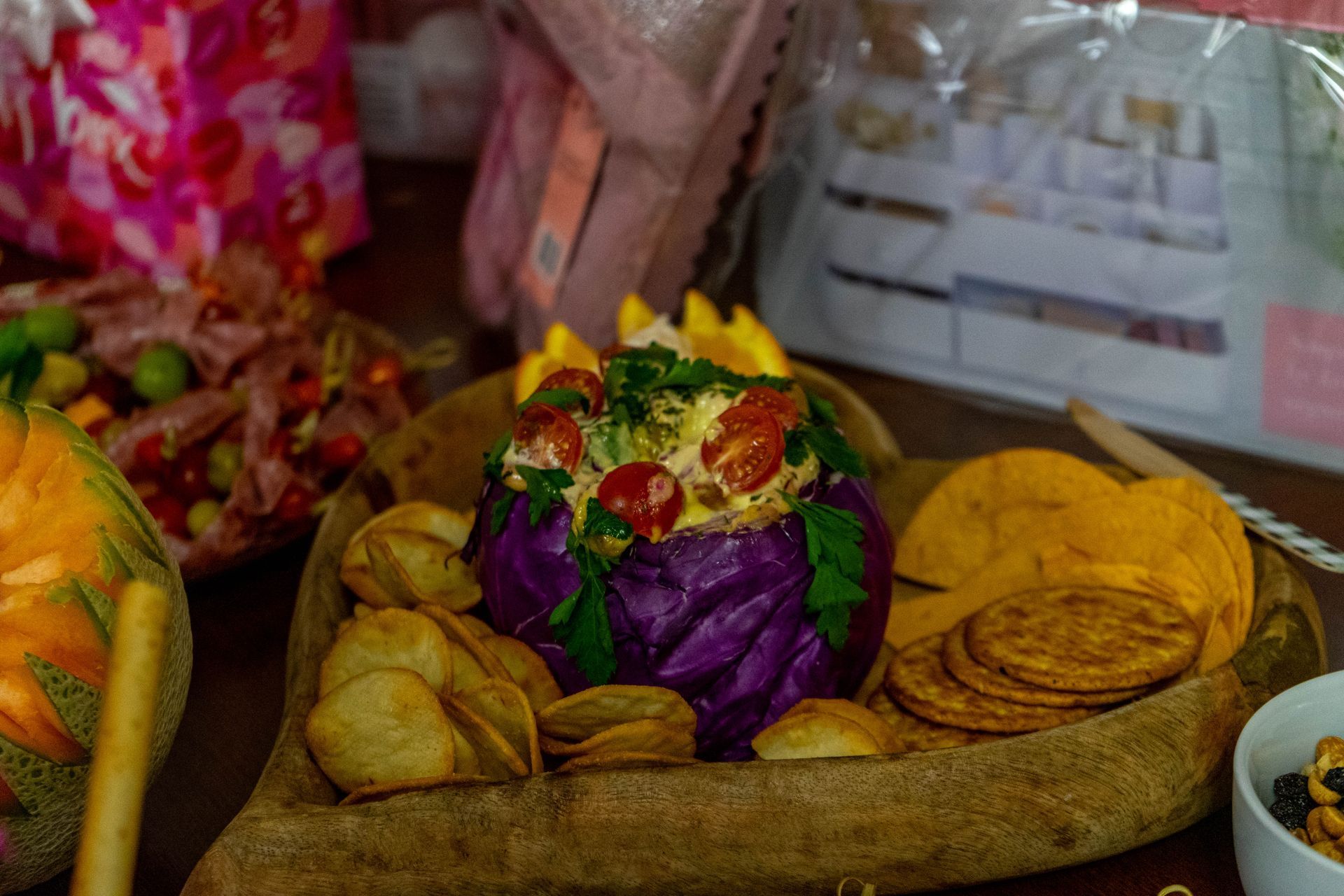 Red cabbage salad with chips and crackers on a wooden platter.