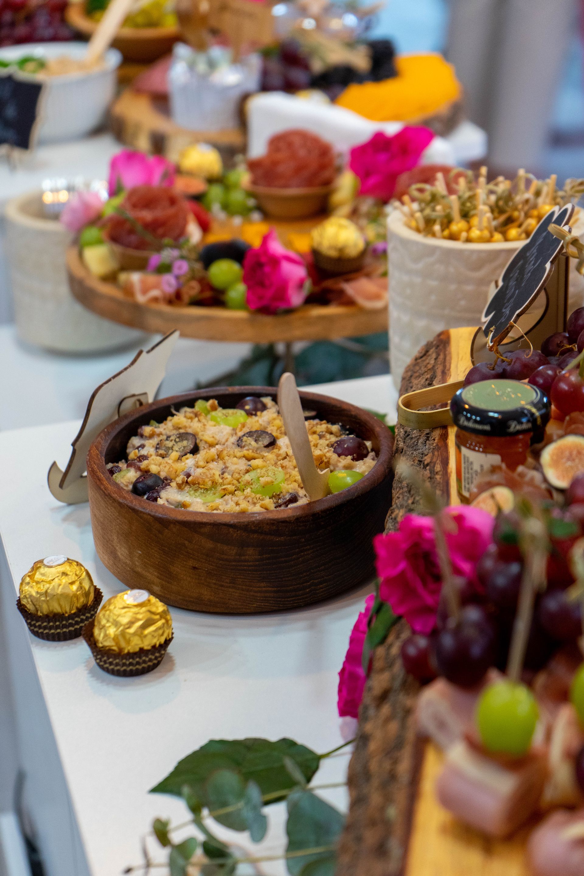 Charcuterie spread with a wooden bowl of food and chocolate.