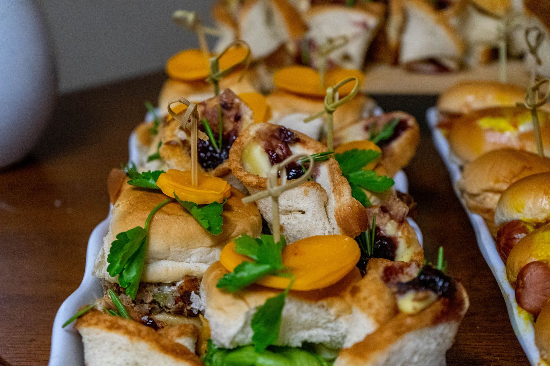 Tray of small, garnished sandwiches with carrot slices and herbs on a table.