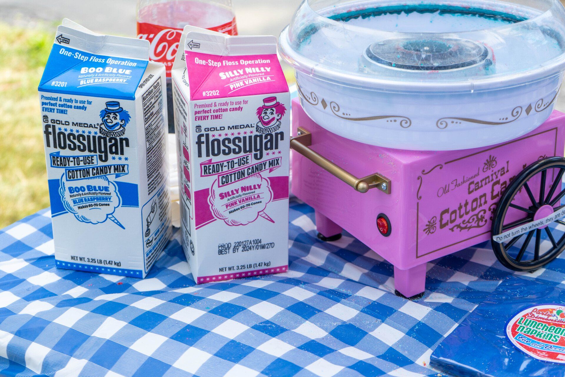 Cotton candy machine with floss sugar cartons on a blue checkered tablecloth.