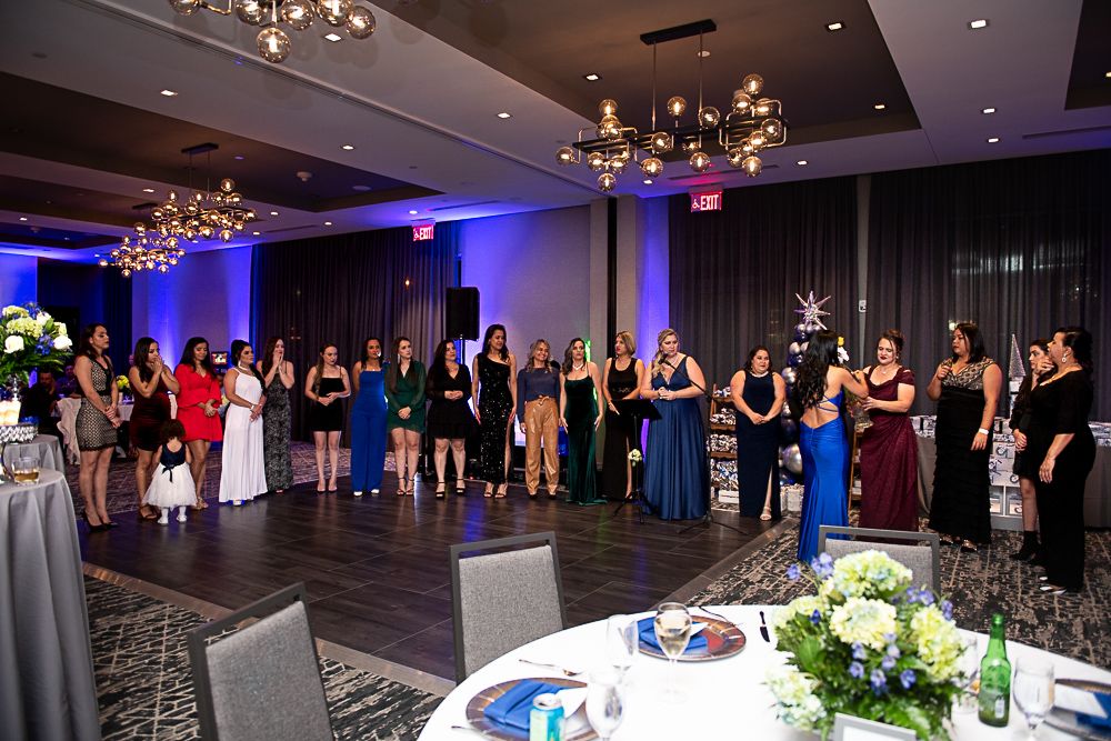 Women in formal wear standing in a ballroom for an event.