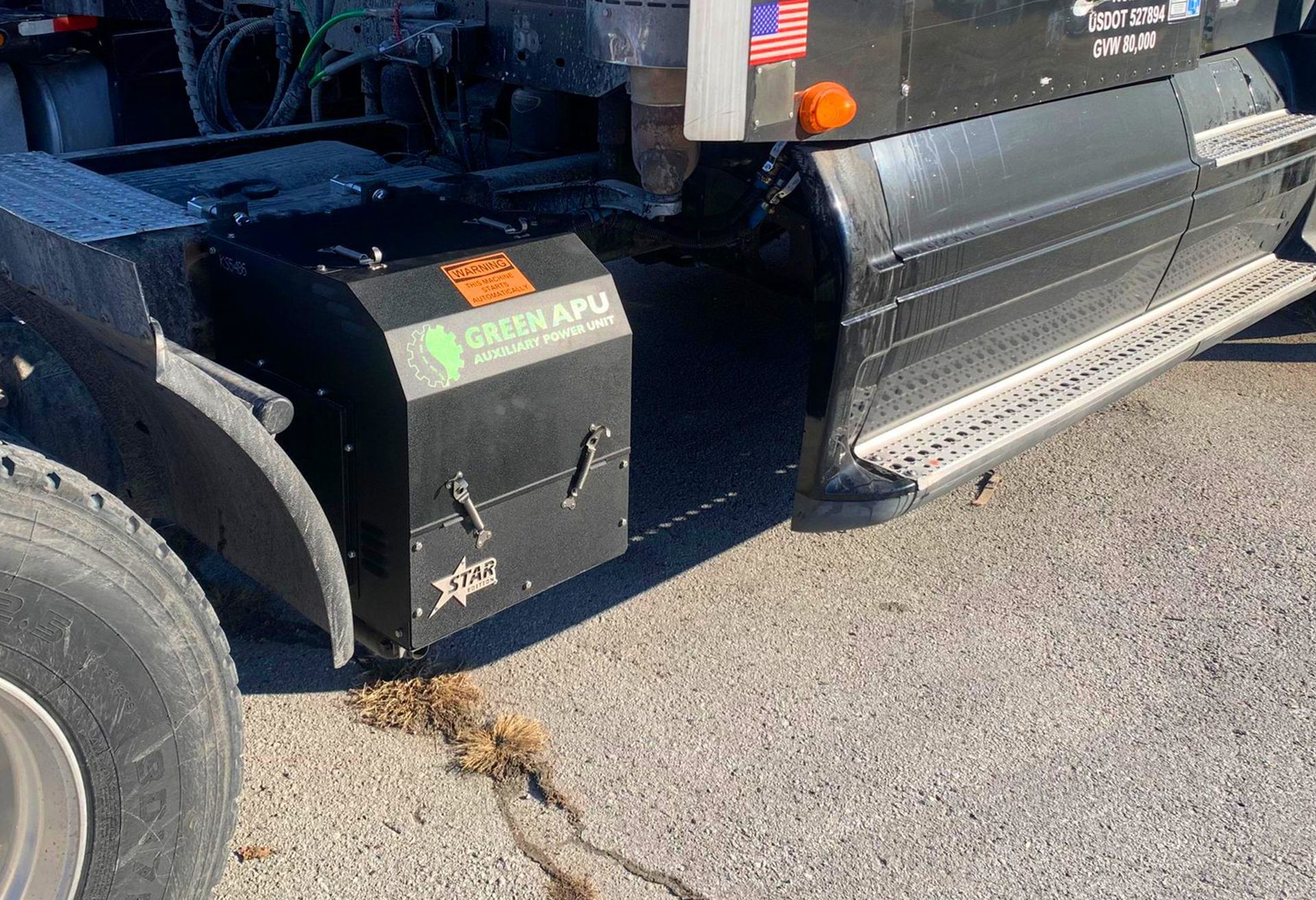 Black truck with side toolbox and running board parked on pavement, close-up of rear side.