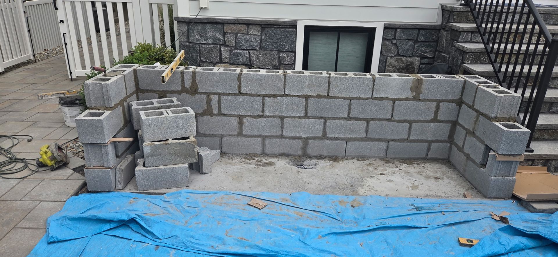 Backyard patio with brick pavers, gray shed, fence, and cloudy sky