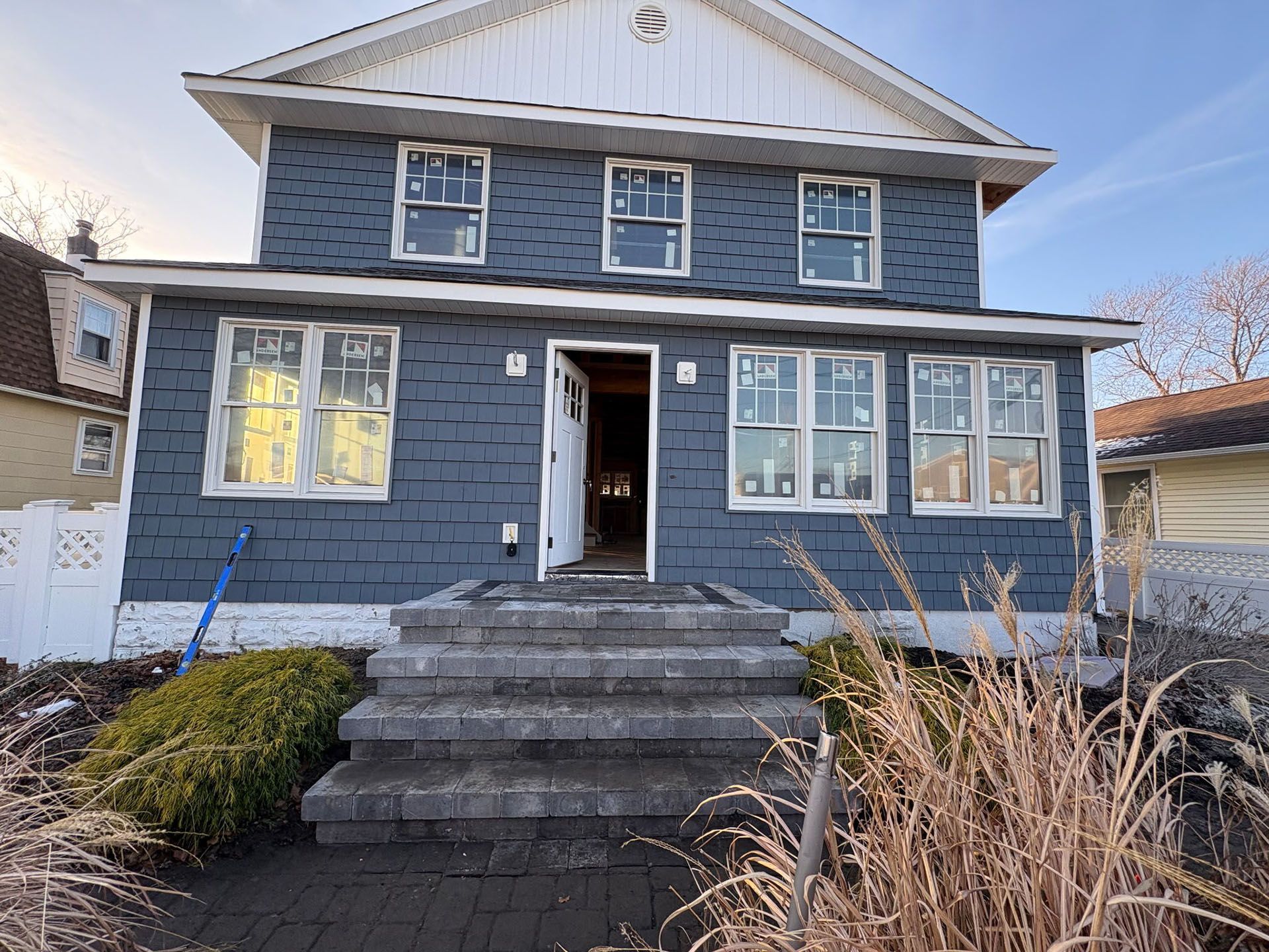 Blue house with stone steps and new windows under construction.