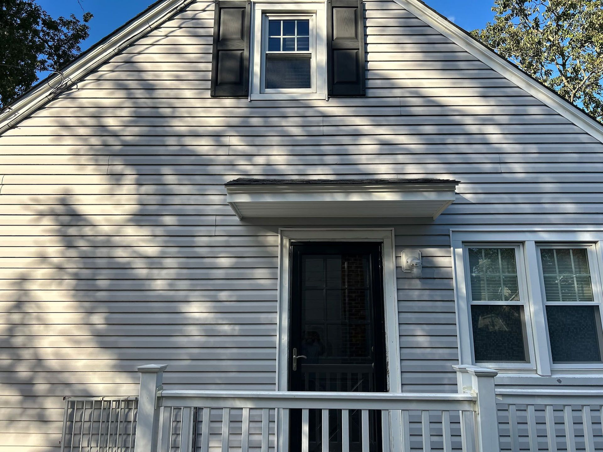 Light gray house with black door, porch, and window shutters.